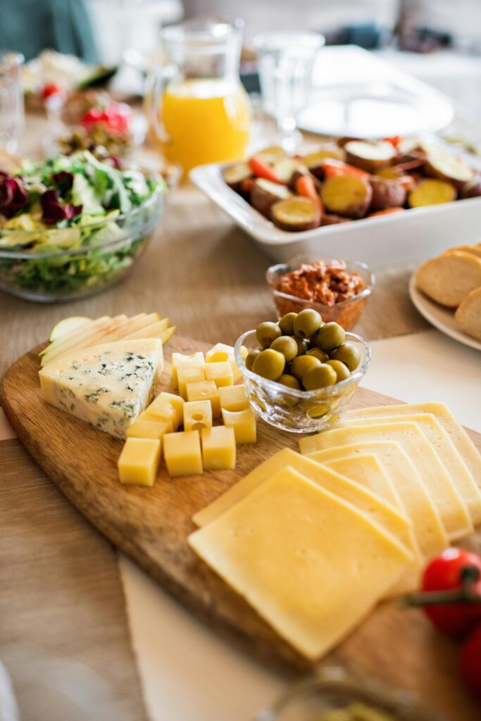 A delicious assortment of cheeses with olives and accompaniments on a wooden platter.